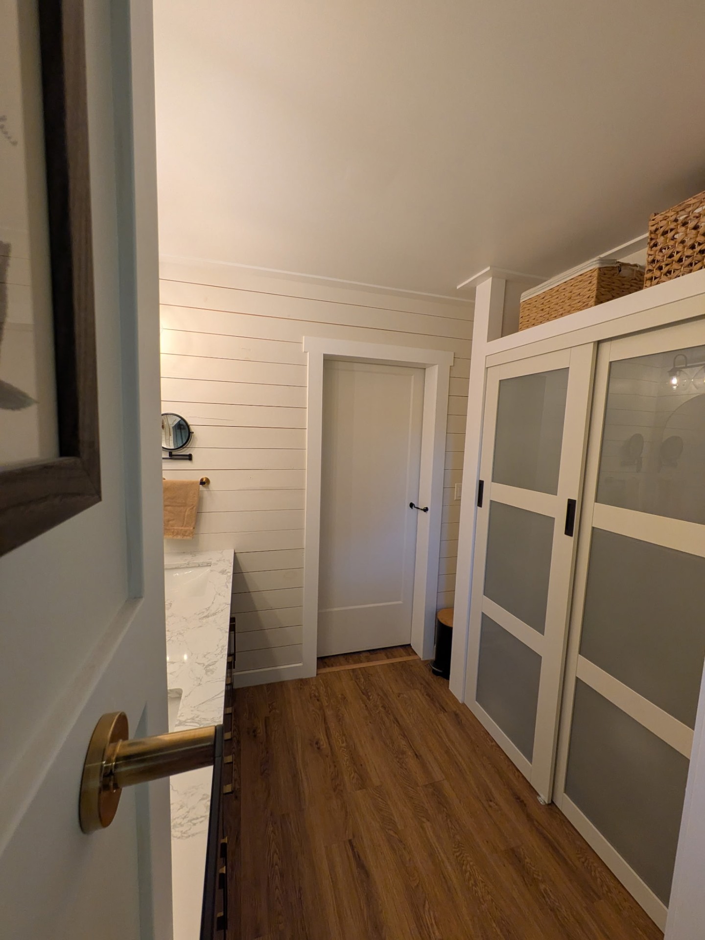 Finished bathroom with shiplap walls and sliding closet doors